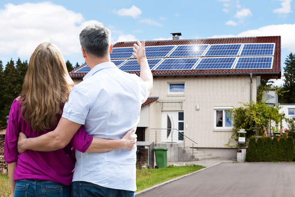 Couple-Standing-In-Front-Of-Solar-Powered-House