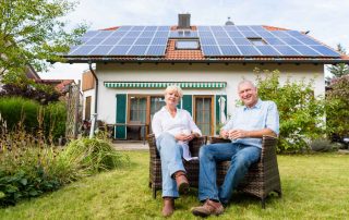 Old-Couple-sitting-in-front-of-their-solar-powered-home (tax credit)